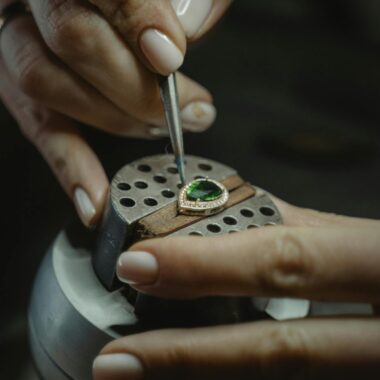 A skilled jeweler carefully crafting an emerald ring using a tweezer, showcasing craftsmanship.