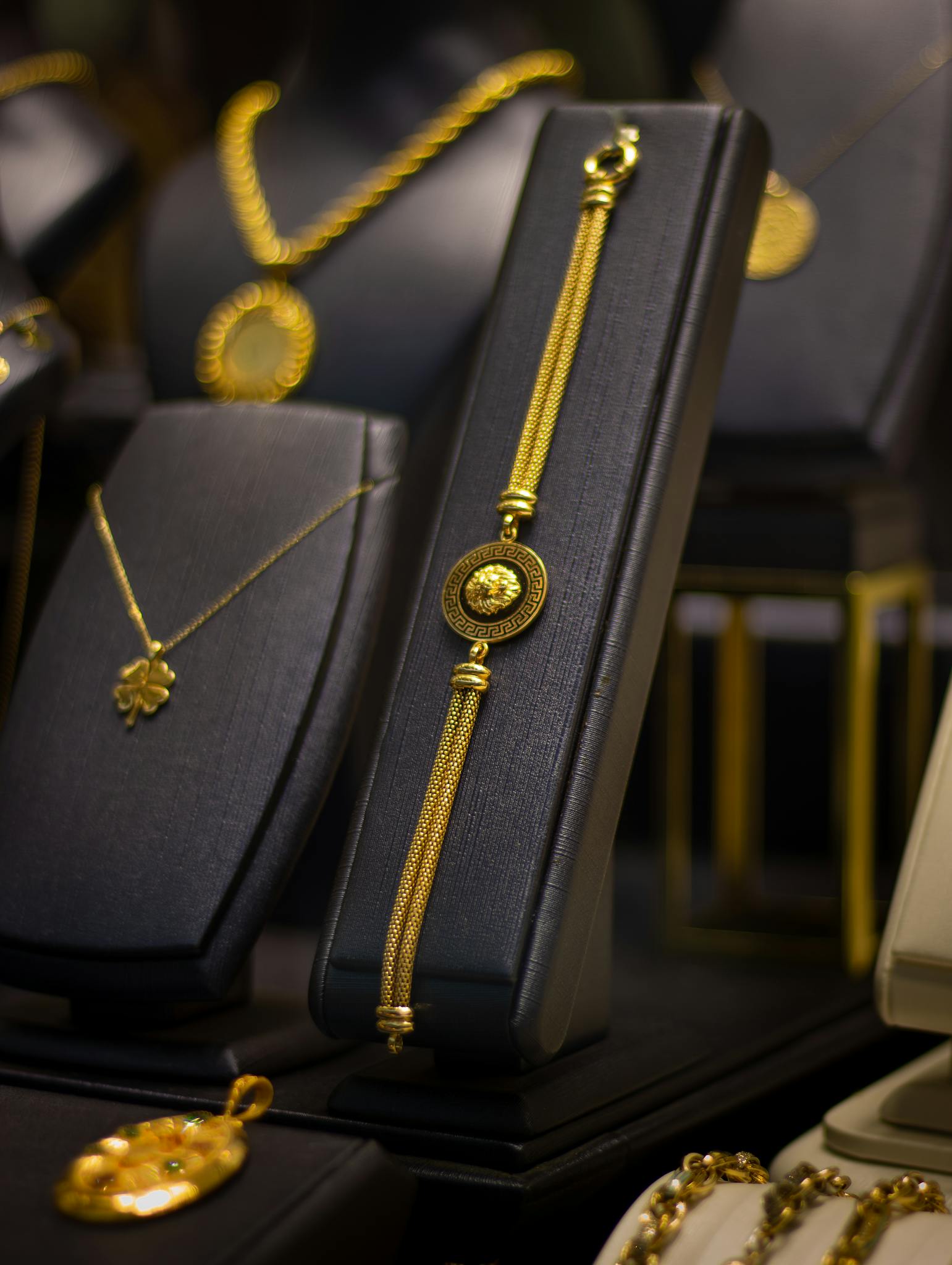 Luxurious gold jewelry elegantly displayed on black stands in a jewelry store.
