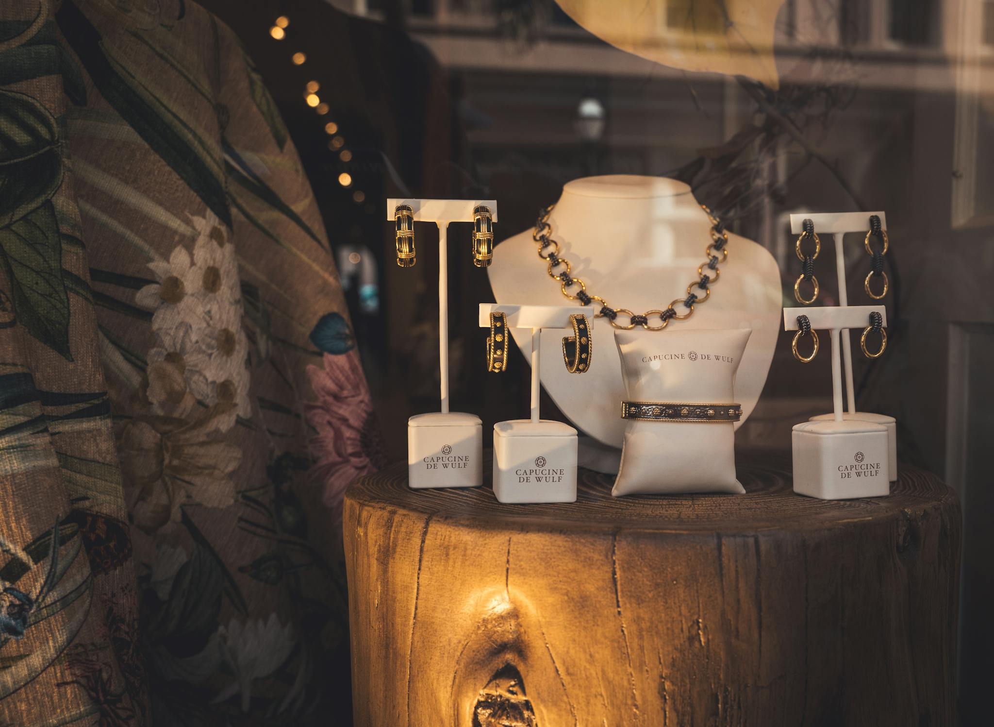 Showcase of elegant gold jewelry pieces on a wooden stand in a store window.